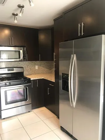 a modern kitchen with stainless steel appliances granite countertop a refrigerator and a stove top oven