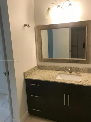 a bathroom with a granite countertop sink and a mirror