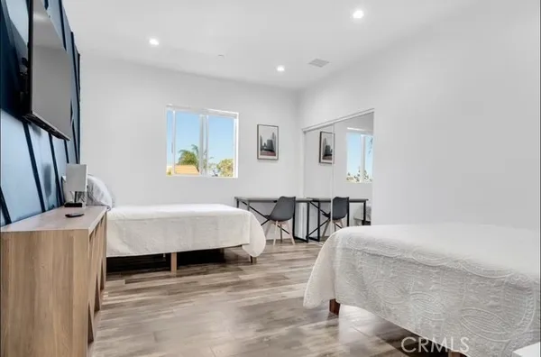a bedroom with a bed a couch and a flat tv screen on the dresser