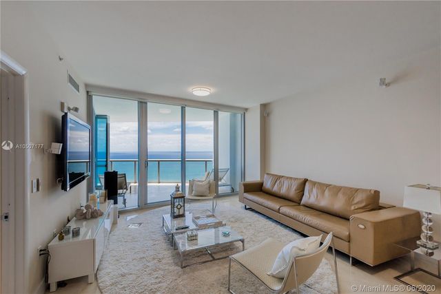 a living room with furniture a flat screen tv and a large window
