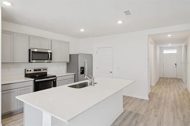 a kitchen with a refrigerator a stove top oven a sink dishwasher and wooden floor