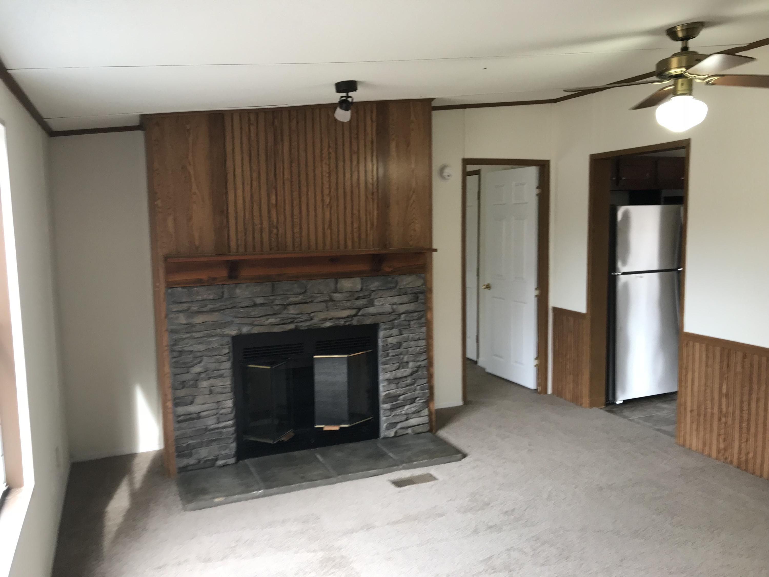 1064 Old Plantation Road Goodview, VA 24095 - Photo 6 of 10 a living room with a fireplace furniture a ceiling fan and a window