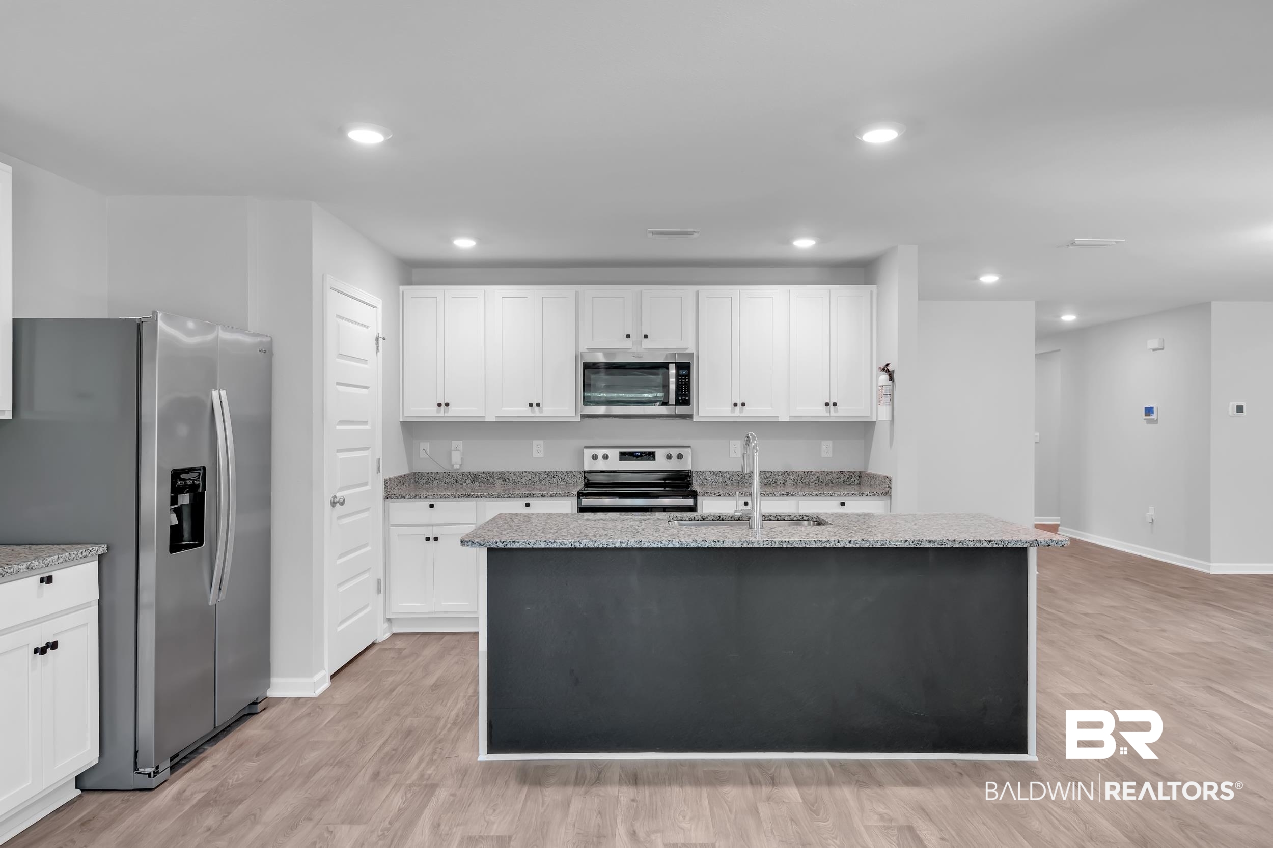 3070 Camino Real Loop Lillian, AL 36549 - Photo 17 of 46 Kitchen featuring a central island with a dark base, light speckled countertops, and wood-finish flooring