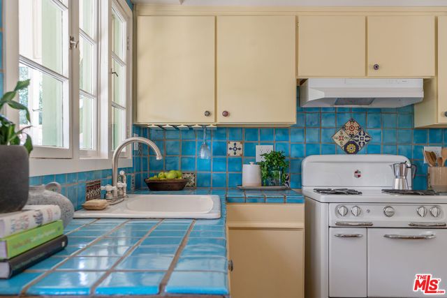 a kitchen with kitchen island a stove a sink and a white cabinets
