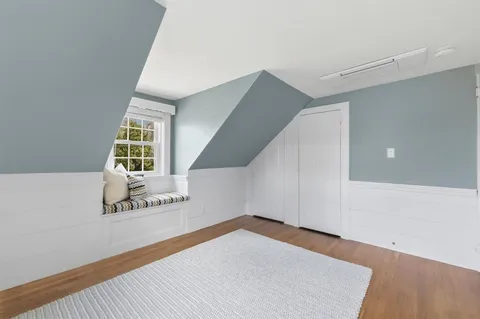 a view of an empty room with wooden floor and stairs
