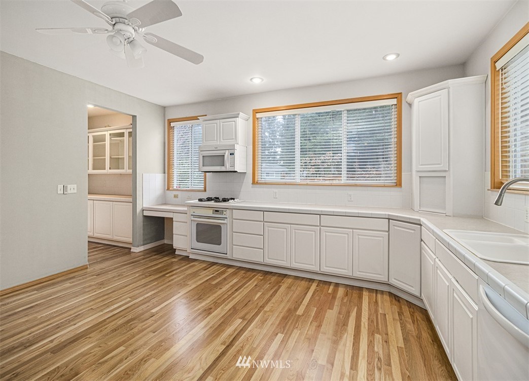3518 Northeast 24th Court Renton, WA 98056 - Photo 10 of 17 a large white kitchen with granite countertop a stove a sink and dishwasher with wooden floor