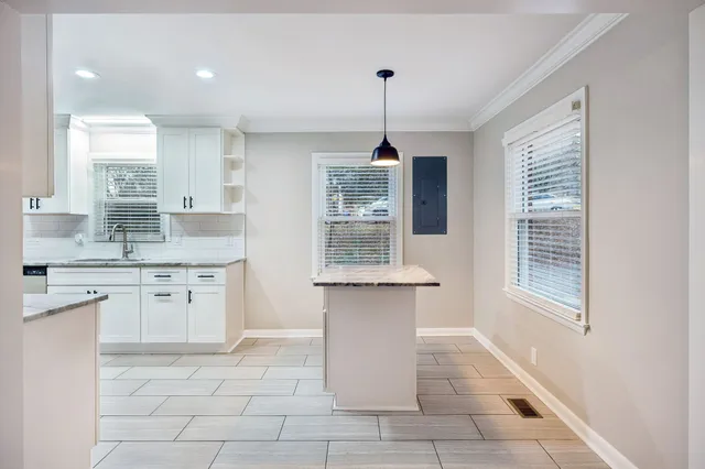 a bathroom with a granite countertop sink a toilet a mirror and a window