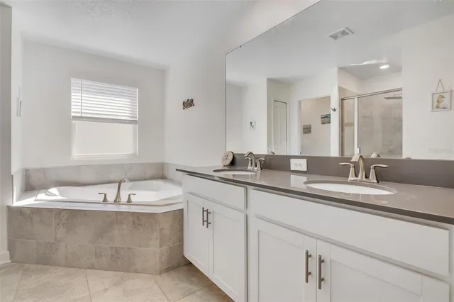 a bathroom with a granite countertop bathtub a sink and a window