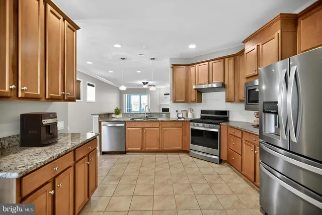 a large kitchen with stainless steel appliances granite countertop a stove a sink dishwasher a refrigerator and cabinets with wooden floor