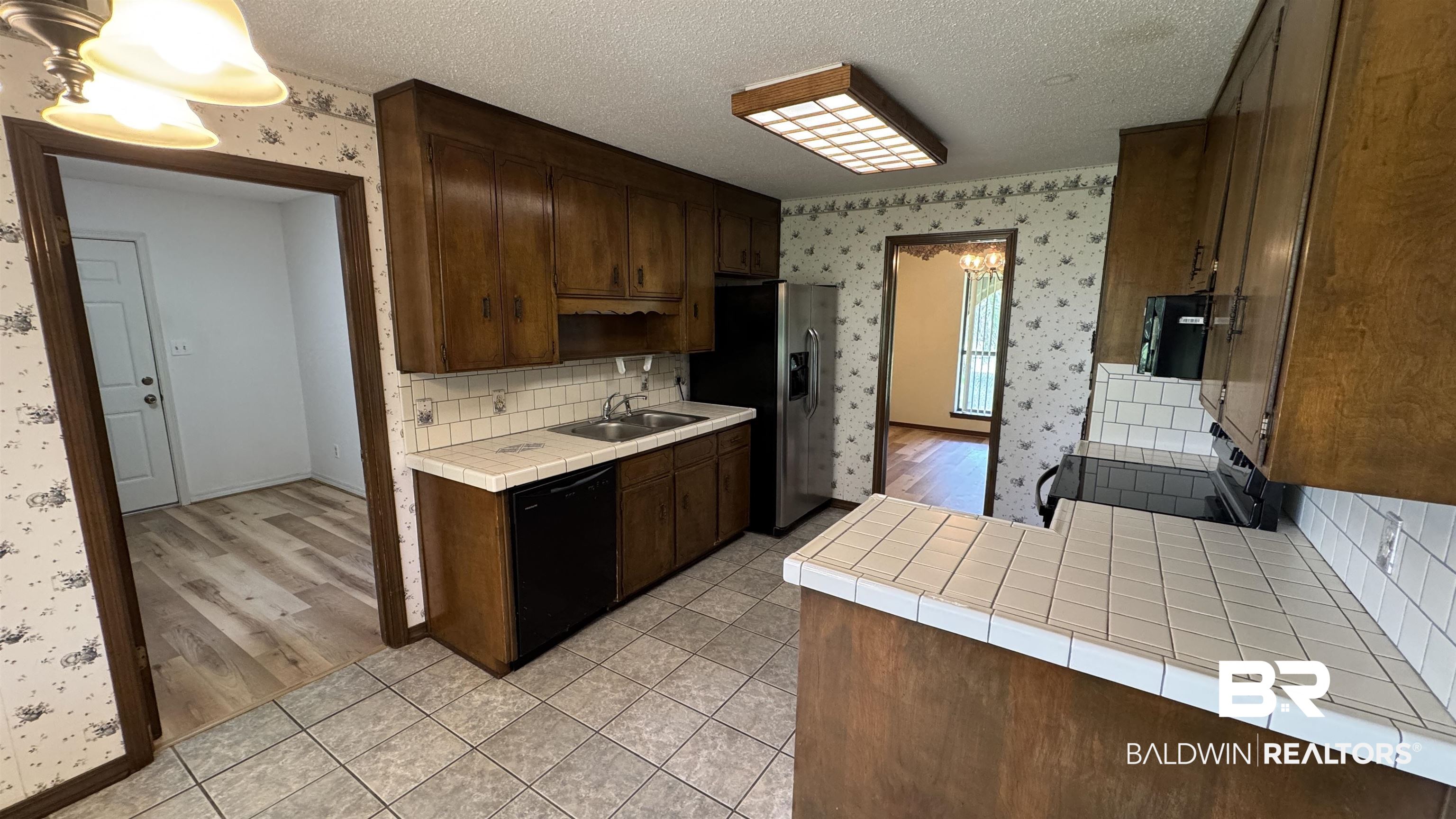 33370 Highway 98 Lillian, AL 36549 - Photo 23 of 58 Kitchen featuring wood cabinetry, white tile countertops, subway tile backsplash, and tile flooring