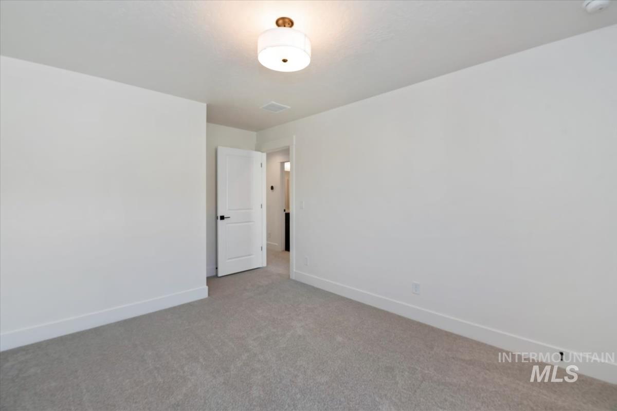 752 South Calhoun Lane Star, ID 83669 - Photo 16 of 45 Spacious room featuring neutral carpet flooring, crisp white walls, and a contemporary ceiling light fixture