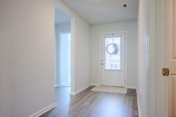 a view of an empty room with wooden floor and a window