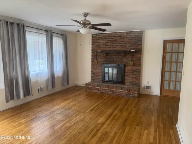 a view of an empty room with wooden floor and a fireplace