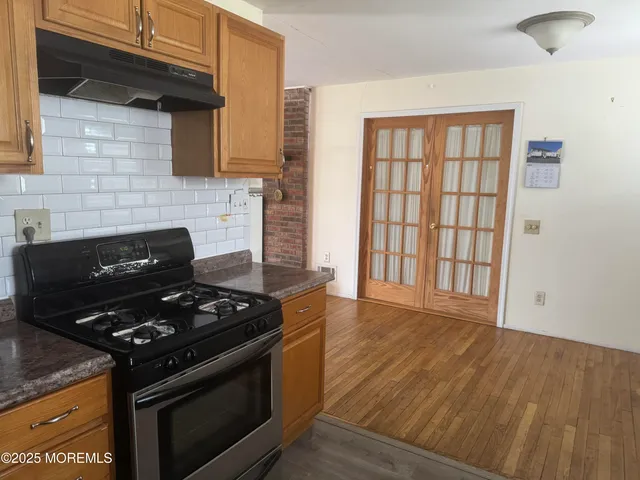 a kitchen with granite countertop a stove and a wooden cabinets