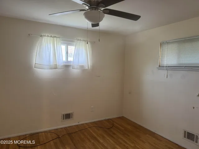 an empty room with a window and ceiling fan