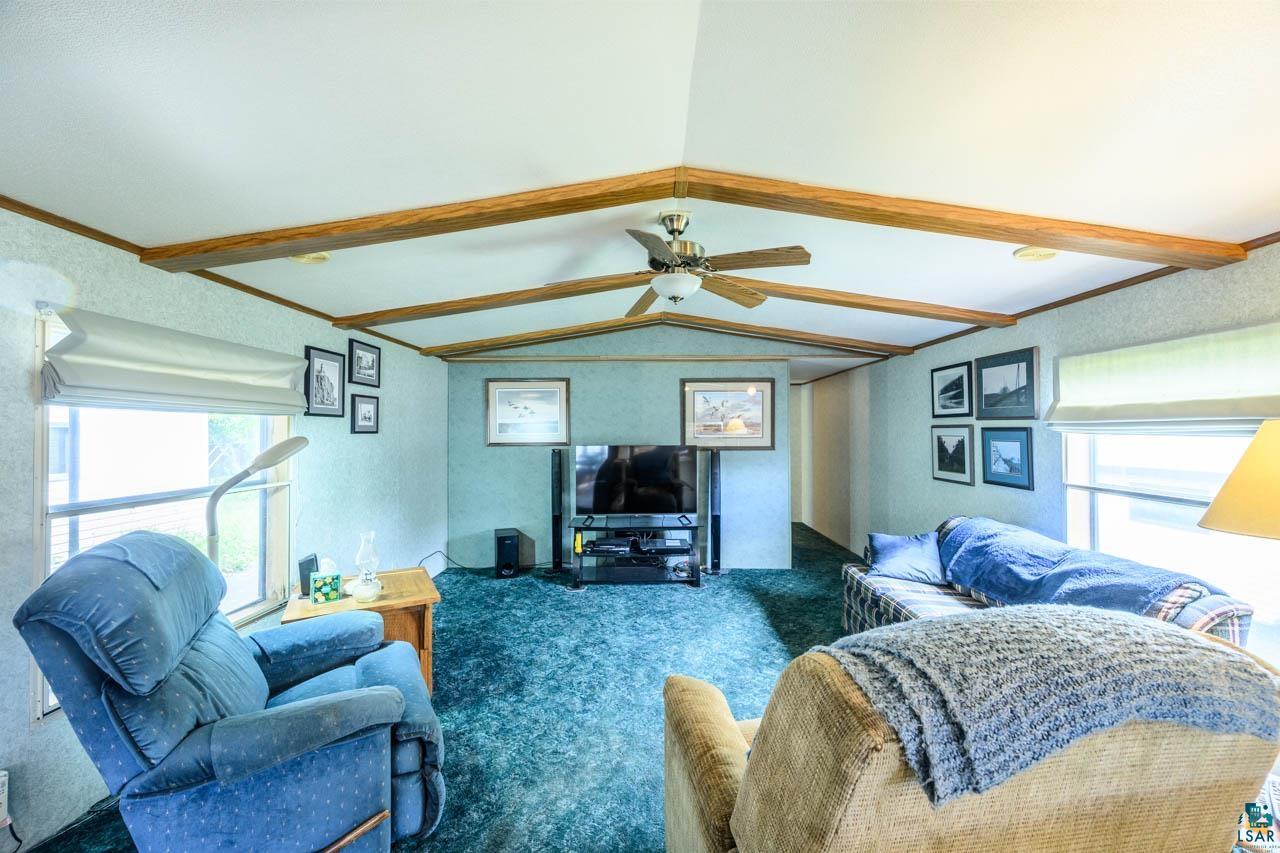 705 4th Street North Biwabik, MN 55708 - Photo 7 of 29 Living area featuring exposed wood beams, vaulted ceiling, ceiling fan, and carpeted flooring