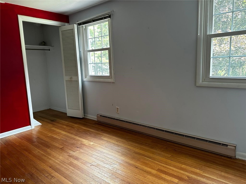 2093 Cambridge Road Coshocton, OH 43812 - Photo 21 of 32 Unfurnished bedroom featuring a baseboard radiator, a closet, and light hardwood / wood-style floors