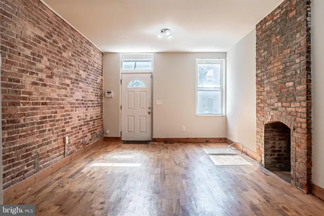 a view of an empty room with wooden floor and a fireplace