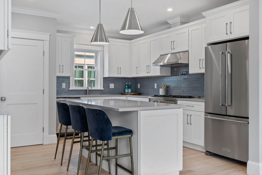 73 R Knoll Street, Unit 73R Boston, MA 02131 - Photo 3 of 11 a kitchen with stainless steel appliances granite countertop a dining table chairs refrigerator and sink