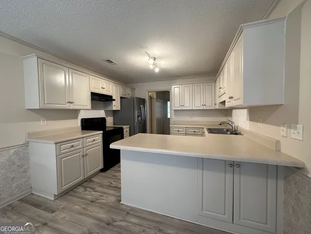 a kitchen with kitchen island white cabinets and stainless steel appliances