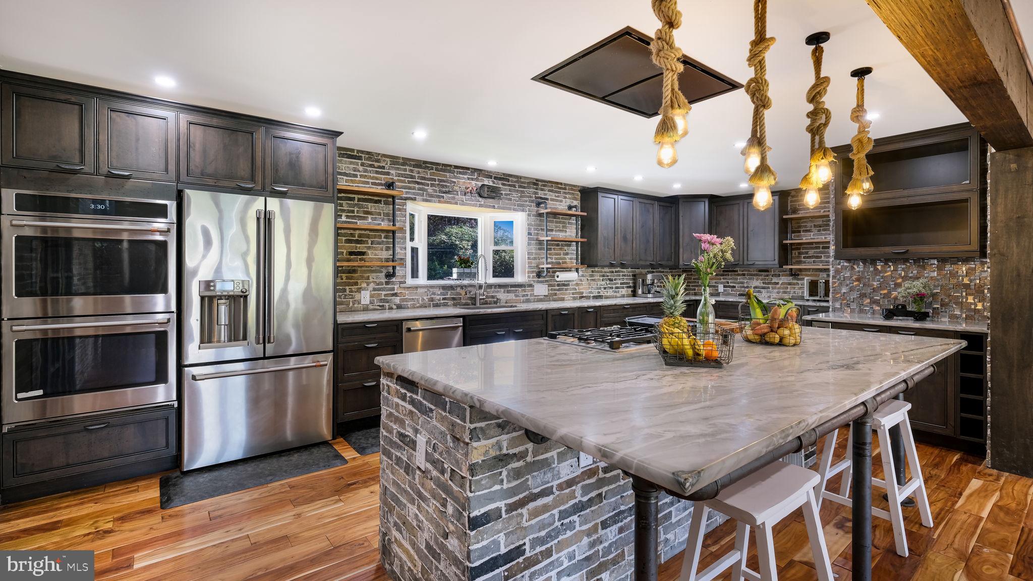 1341 Carol Road Jenkintown, PA 19046 - Photo 30 of 56 a kitchen with stainless steel appliances granite countertop a kitchen island a stove a refrigerator a sink a dining table and chairs with wooden floor