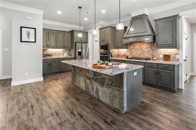 a kitchen with stainless steel appliances granite countertop a stove a sink dishwasher and a refrigerator with wooden floor