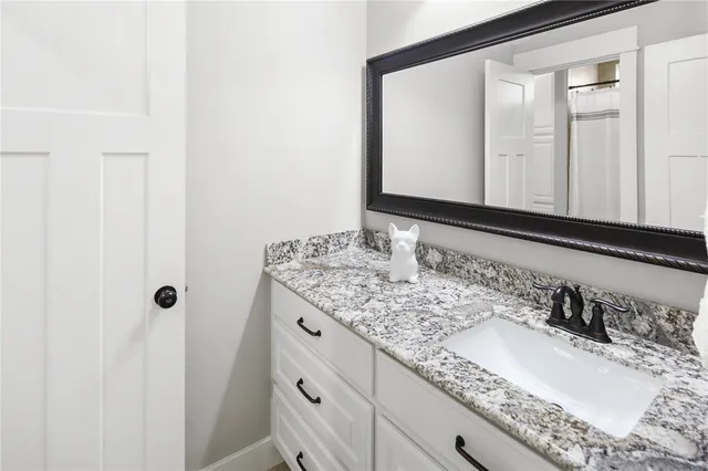 a bathroom with a granite countertop sink and a mirror