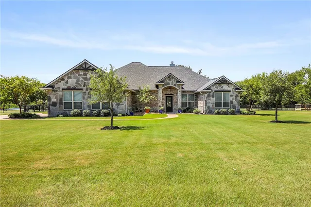a view of a house with a big yard and large trees
