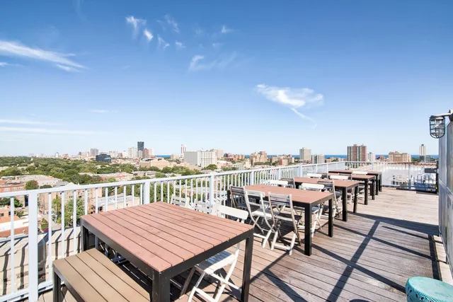 a view of a rooftop deck with chairs and a dining table