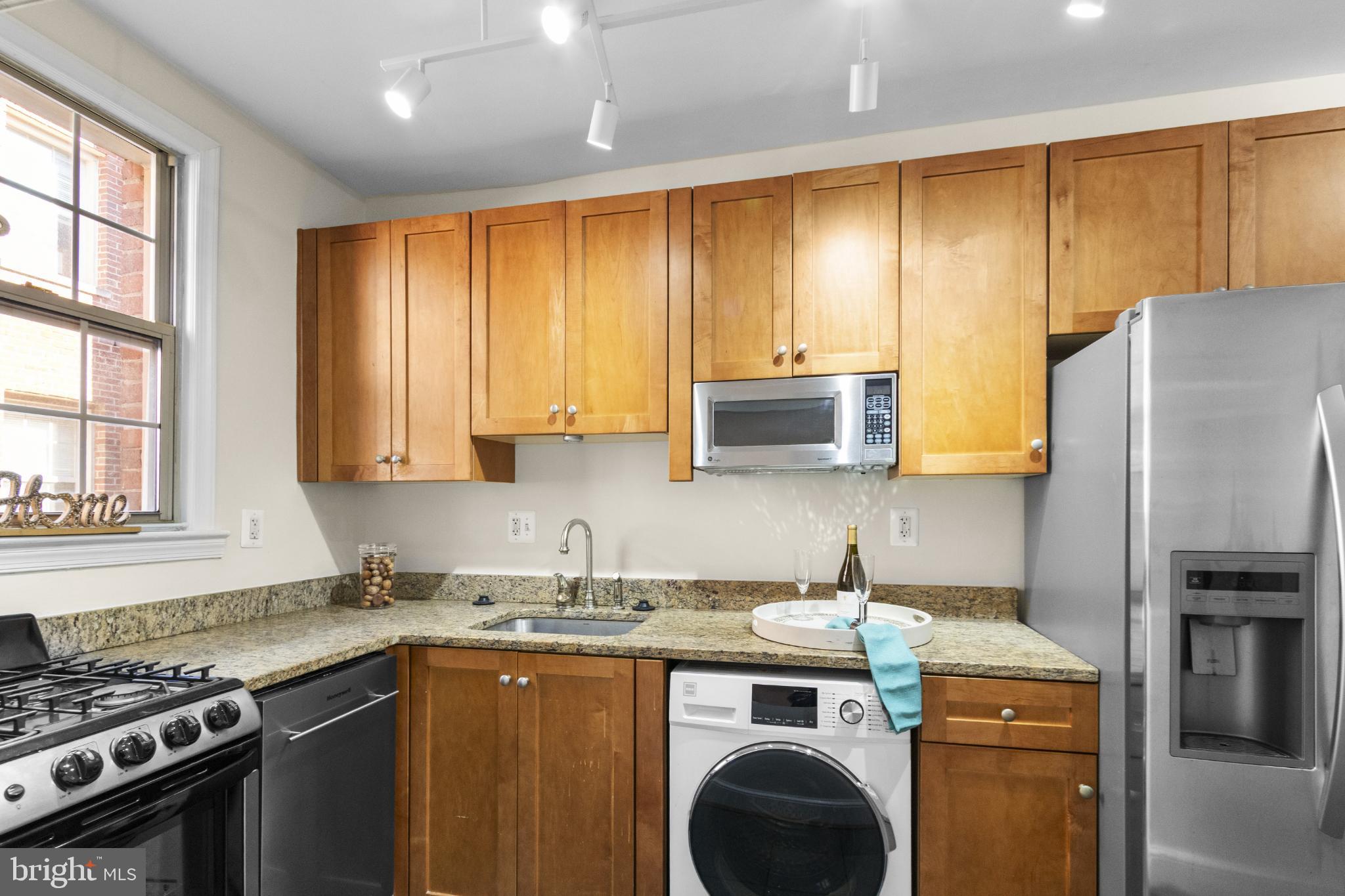 1441 Euclid Street Northwest, Unit 207 Washington, DC 20009 - Photo 10 of 23 a kitchen with stainless steel appliances granite countertop a stove a sink dishwasher and a refrigerator with wooden cabinets