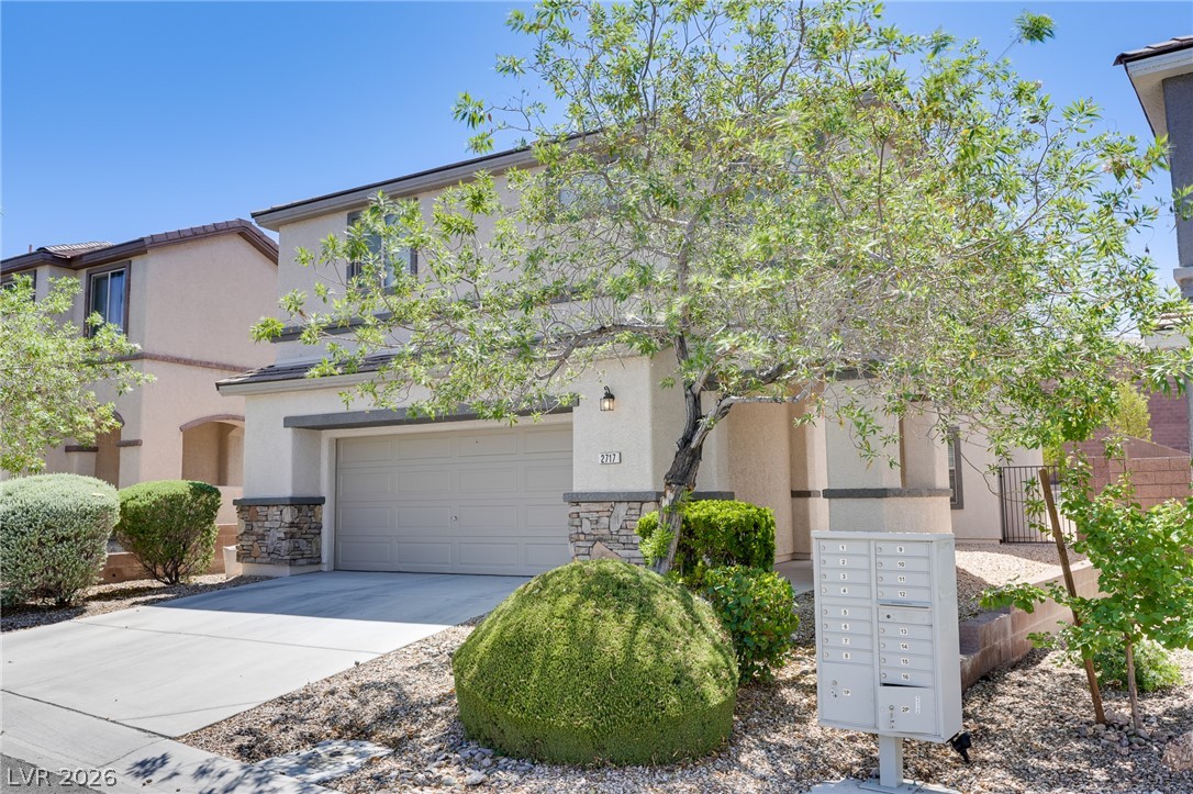 2717 Rimbaud Street Henderson, NV 89044 - Photo 2 of 34 A cream-colored home presents with an attached garage and a concrete driveway, complemented by xeriscaped front yard landscaping.
