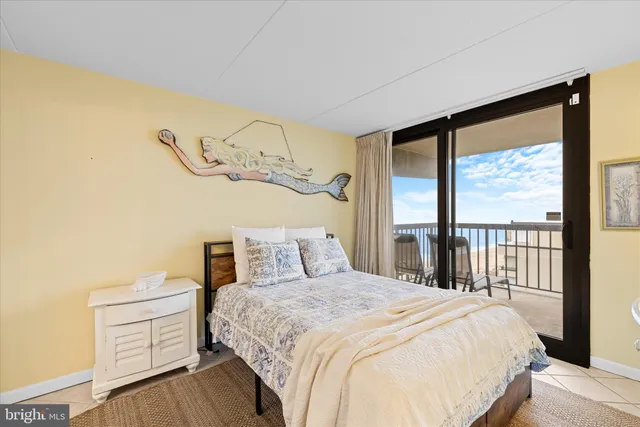 a bedroom with a large bed and a flat tv screen on dresser next to a window