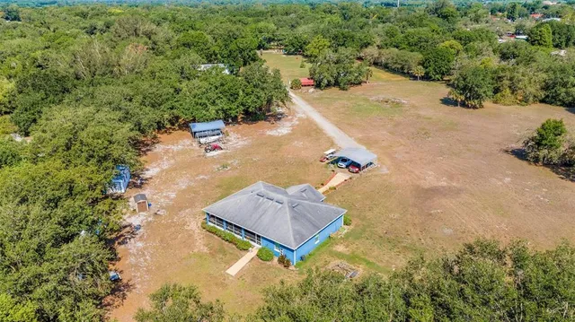 an aerial view of a house with a yard and trees all around