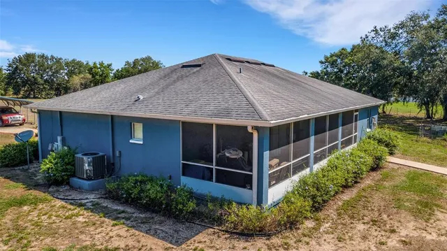 a view of a house with a yard plants and large tree