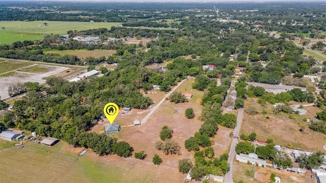 an aerial view of a residential houses with outdoor space and trees
