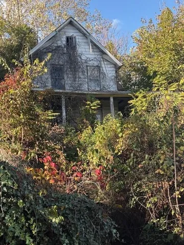 a brick house with a small yard and large trees