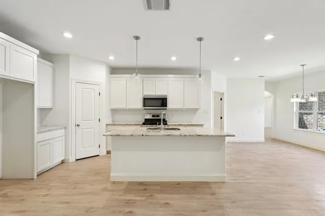 a view of a kitchen with kitchen island a sink stainless steel appliances and cabinets