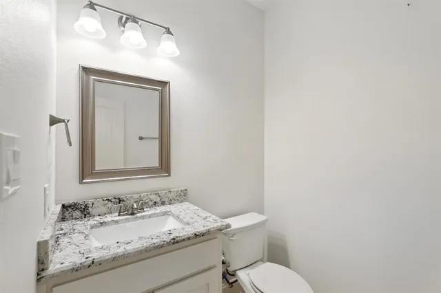 a bathroom with a granite countertop sink and a toilet