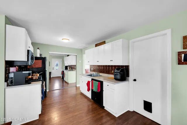a living room with stainless steel appliances furniture a kitchen view and a refrigerator
