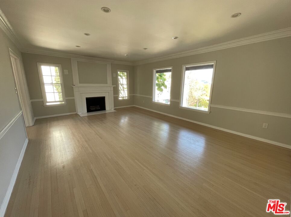 437 Shirley Place, Unit D Beverly Hills, CA 90212 - Photo 2 of 16 an empty room with wooden floor and fireplace