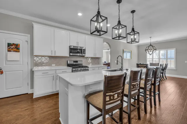 a kitchen with stainless steel appliances a table chairs refrigerator and microwave