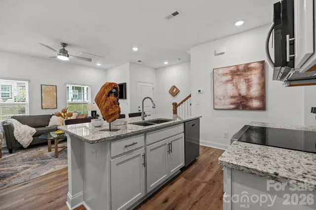 a kitchen with stainless steel appliances granite countertop a sink dishwasher a stove and a refrigerator with wooden floor