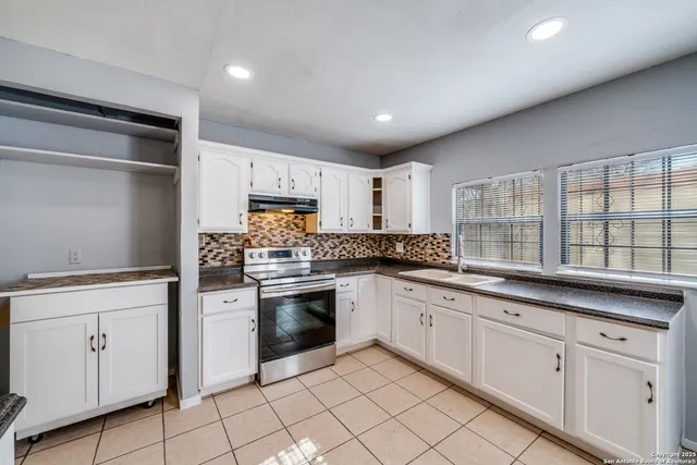 a kitchen with white cabinets appliances and a sink