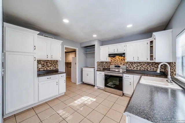 a kitchen with granite countertop a stove top oven and cabinets