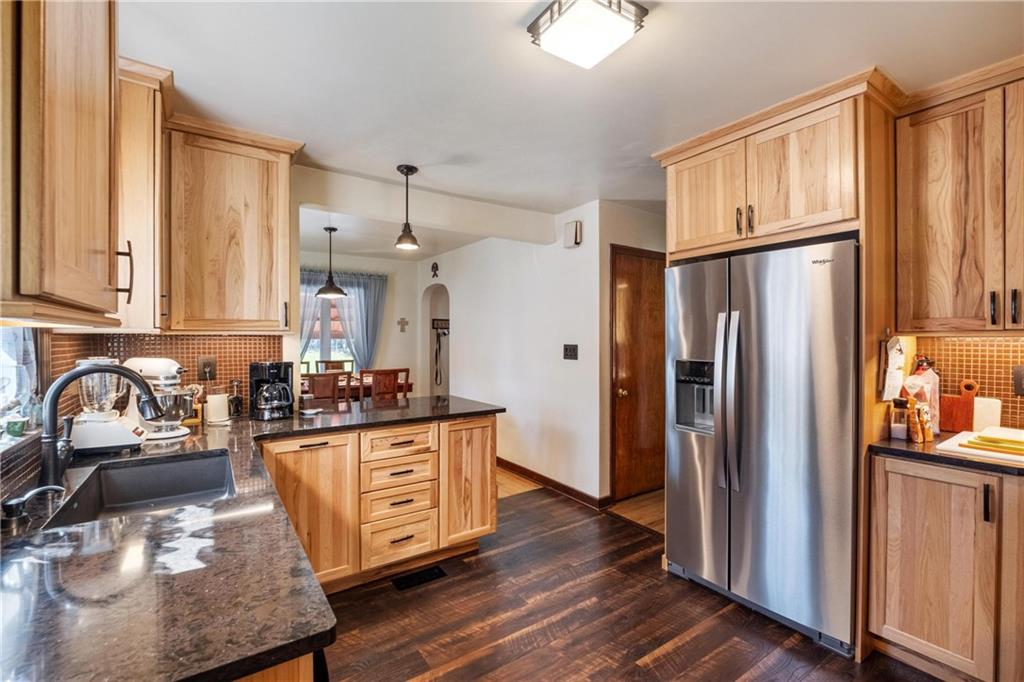 696 Filmore Road Pittsburgh, PA 15221 - Photo 17 of 37 a kitchen with stainless steel appliances granite countertop a refrigerator a stove and a sink with wooden floors
