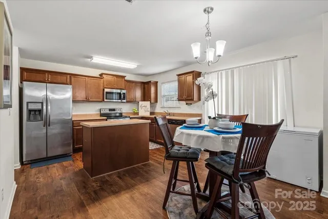 a kitchen with granite countertop a refrigerator a stove a sink a dining table and chairs