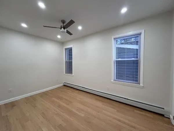 an empty room with a ceiling fan & windows