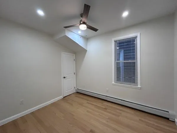 an empty room with wooden floor cabinet and windows