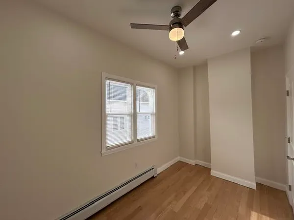 an empty room with wooden floor ceiling fan and windows