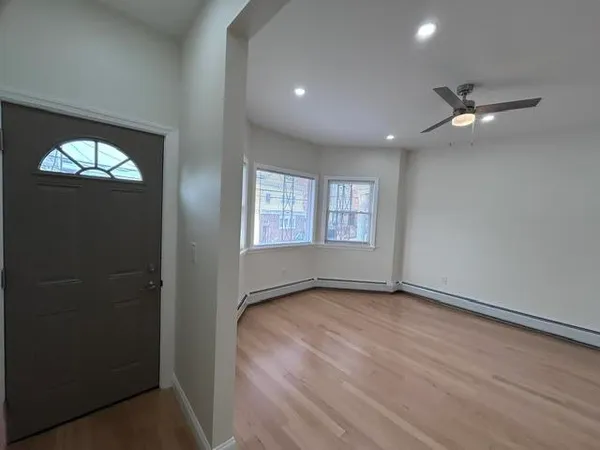 a view of empty room with wooden floor and fan